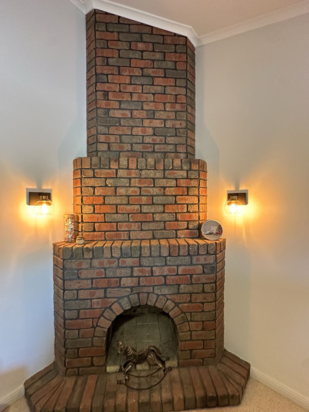 Warm glass wall lights installed either side of a brick fireplace