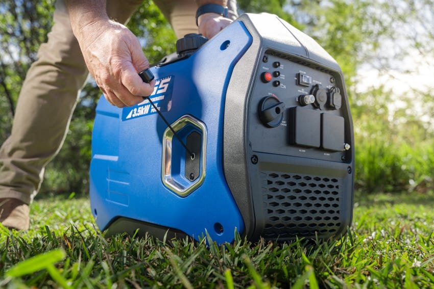 A person pulling the start cord on a portable inverter generator outdoors on grass